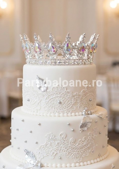 Topper Tort Coronita Argintie cu Cristale Iridescente (Metal) 15 cm Un topper decorativ premium pentru tort sub forma unei coronite argintii din metal. Coronita are diametrul de 15 cm si este bogat ornamentata cu strasuri clare si pietre mari in forma de lacrima care au reflexii iridescente multicolore tip aurora boreala. Produsul este asezat elegant pe un tort alb supraetajat
