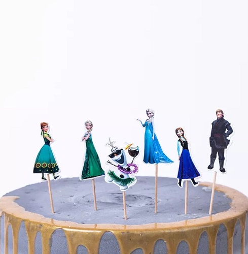 Set 24 Toppere Decorative Toppere Briose Frozen Elsa Un set de scobitori decorative tip topper pentru briose si tort cu tematica Frozen. Imaginea prezinta sase personaje infipte intr-un tort gri cu glazura aurie